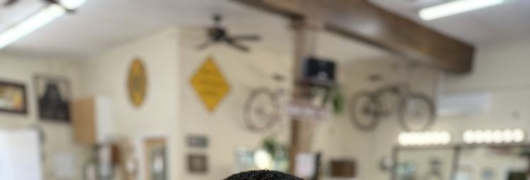 Inside Uptown Barber Shop: a ceiling fan, a yellow road sign and two vintage bicycles hung on the wall under a wooden beam